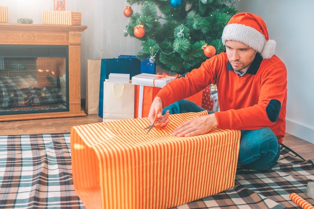 Il giovane serio si siede sulla coperta e taglia la carta con le forbici