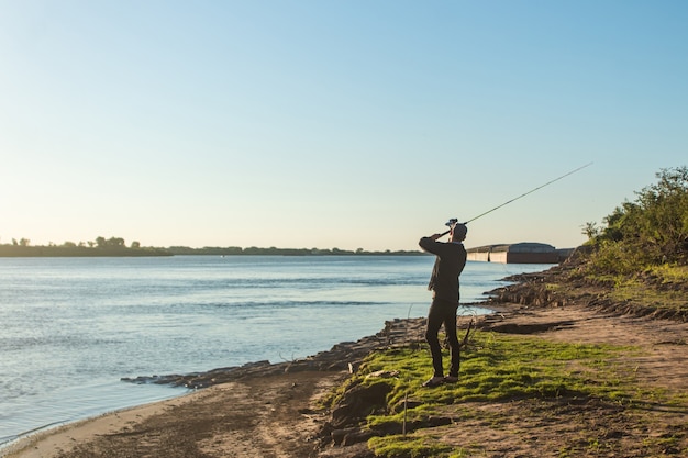 Il giovane si preparava a lanciare la sua canna da pesca nell'acqua al bordo del fiume.