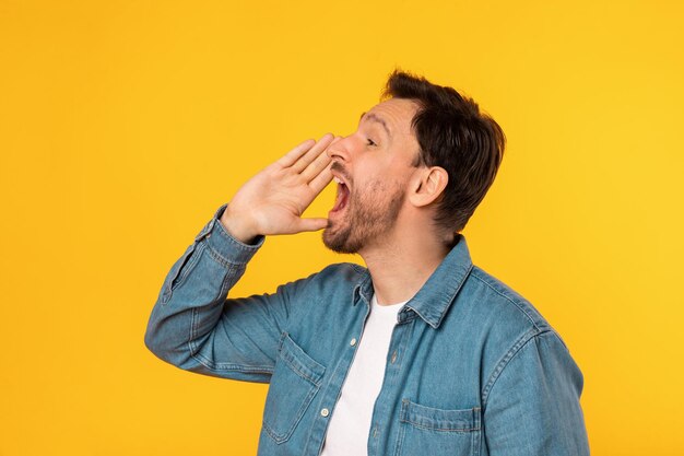 Il giovane si trova contro uno sfondo giallo vivido con la bocca spalancata come se urlasse o chiamasse