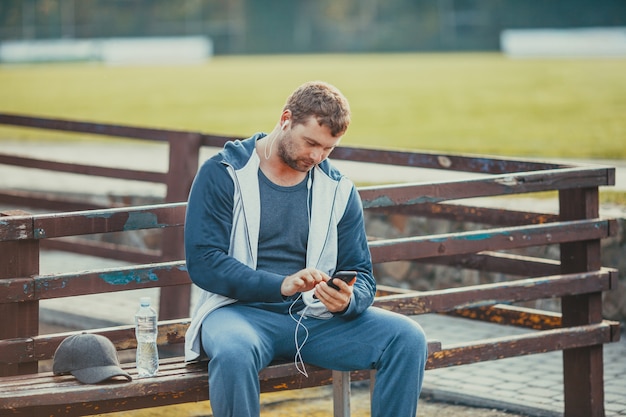 Il giovane sintonizza la musica preferita sullo smartphone prima dell'allenamento