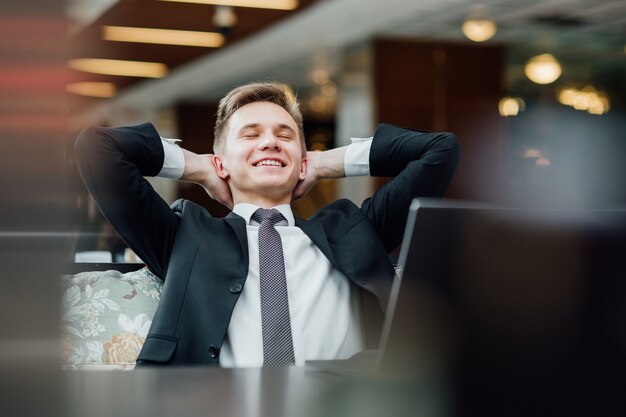 Il giovane sogna la vacanza, si rilassa dopo una dura giornata di lavoro dopo un laptop nella caffetteria