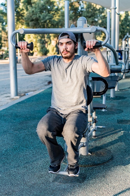 Il giovane solleva il proprio peso in attrezzature per il fitness