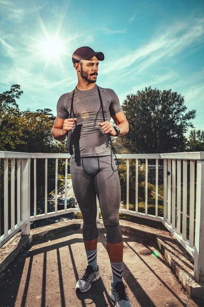 Il giovane sportivo urbano sta riposando dopo l'allenamento nel parco e distoglie lo sguardo.