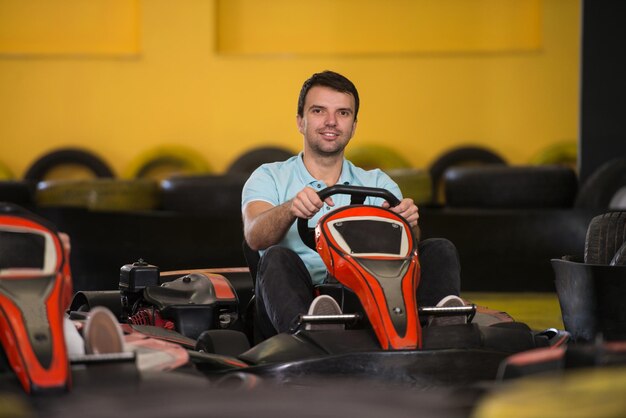 Il giovane sta guidando l'auto di GoKart con velocità in una pista da corsa del parco giochi Go Kart è un popolare sport motorio per il tempo libero