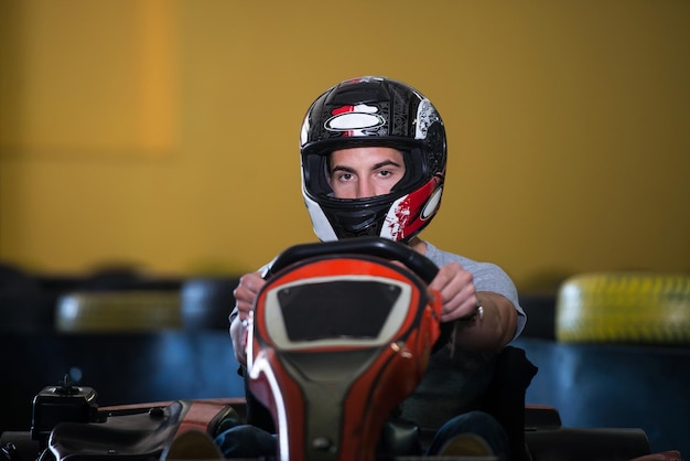 Il giovane sta guidando l'auto di GoKart con velocità in una pista da corsa del parco giochi Go Kart è un popolare sport motorio per il tempo libero