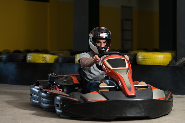 Il giovane sta guidando l'auto di GoKart con velocità in una pista da corsa del parco giochi Go Kart è un popolare sport motorio per il tempo libero