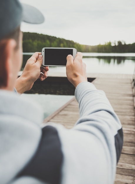 Il giovane sta scattando una foto seduto su un molo