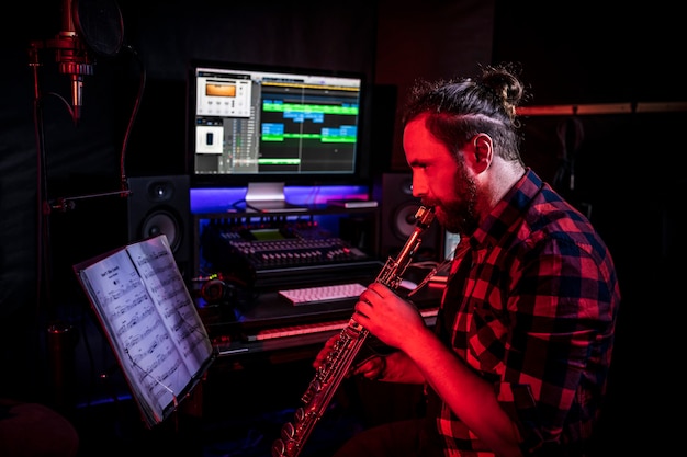 Il giovane sta suonando uno strumento musicale in studio per registrare la sua canzone nuova di zecca