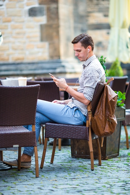 Il giovane sta tenendo il cellulare all'aperto sulla strada. Ragazzo che utilizza smartphone mobile.