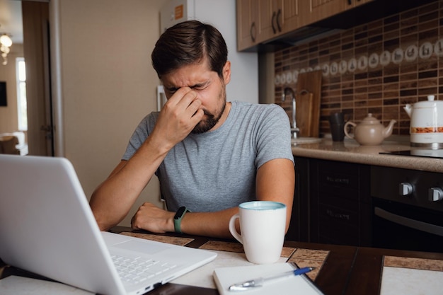 Il giovane stanco sente dolore affaticamento degli occhi dal lavoro al computer