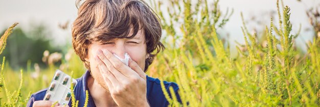 Il giovane starnutisce a causa di un'allergia al formato lungo della bandiera dell'ambrosia