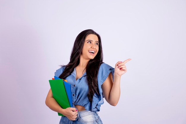 Il giovane studente adolescente in abbigliamento denim tiene i punti dei libri per liberare spazio per il testo