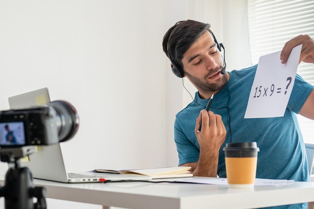 Il giovane studente caucasico intelligente dell'uomo d'affari, l'insegnante tutor indossa l'auricolare, guarda la fotocamera, parla di saluto durante le riprese video registrate. La tecnologia impara insegna nella chat online, distanza nel concetto di istruzione.