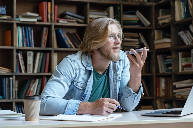 Il giovane studente che tiene il telefono attiva il riconoscimento vocale digitale virtuale