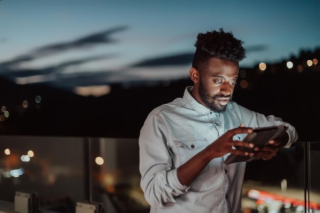 Il giovane su una strada urbana della città di notte manda un sms su uno smartphone con bokeh e luci al neon della città sullo sfondo. Foto di alta qualità. Foto di alta qualità