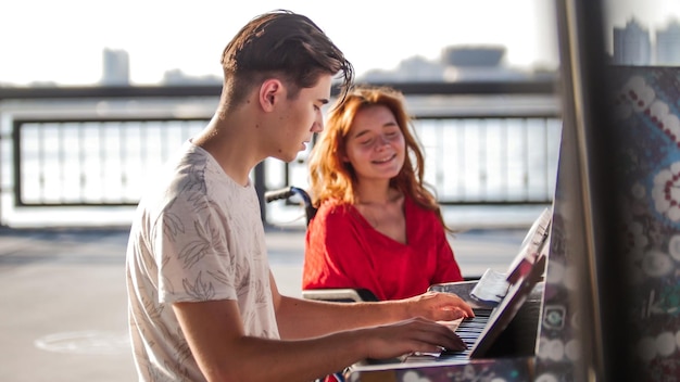 Il giovane suona il pianoforte per una ragazza rossa su una sedia a rotelle