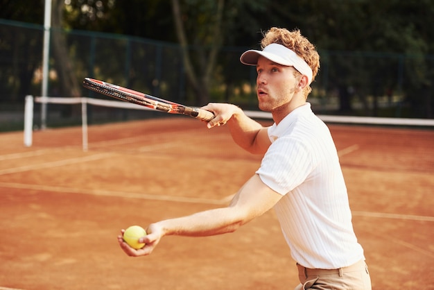 Il giovane tennista in abiti sportivi è in campo all'aperto.