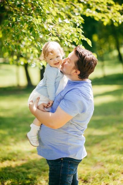 Il giovane tiene la piccola figlia tra le braccia nel parco