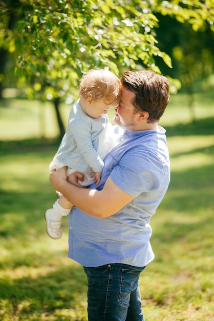 Il giovane tiene la piccola figlia tra le braccia nel parco