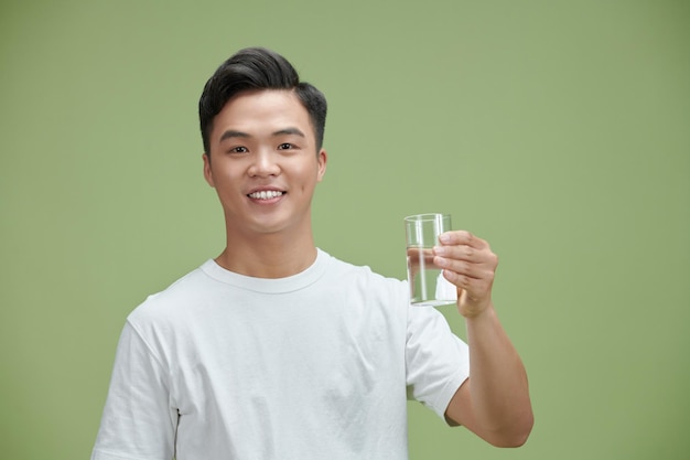 Il giovane tiene un bicchiere di acqua pura