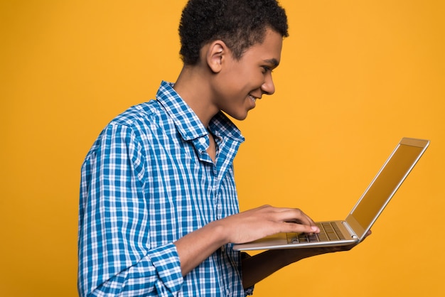 Il giovane tipo afroamericano lavora con il computer portatile.