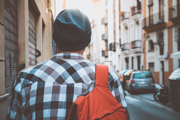 Il giovane turista con lo zaino sta camminando per la strada in una città europea.