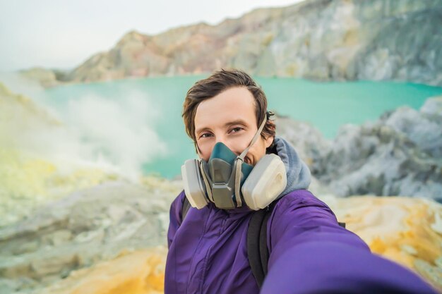 Il giovane turista fa un selfie in piedi sul bordo del cratere del vulcano Ijen o kawah