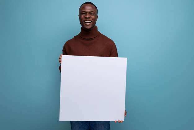 Il giovane uomo africano pubblicizza il prodotto con display su foglio bianco