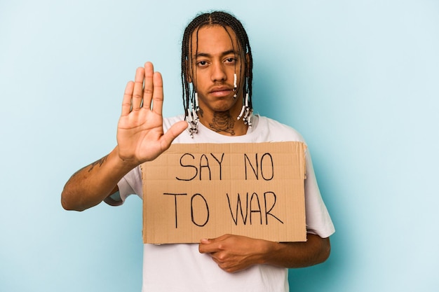 Il giovane uomo afroamericano che tiene non dice cartello di guerra isolato su sfondo blu