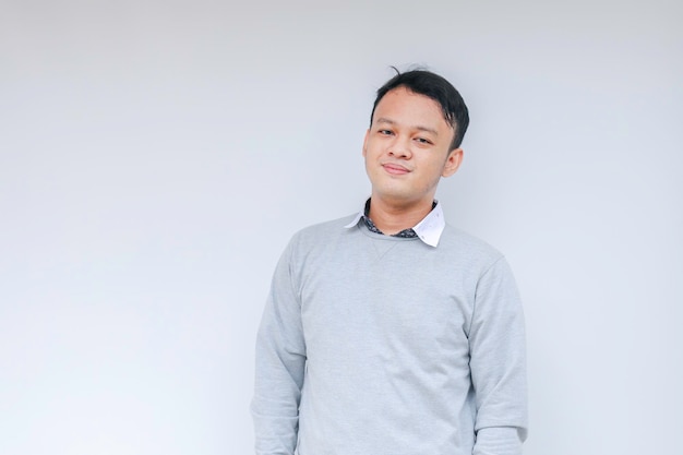 Il giovane uomo asiatico che indossa una camicia bianca sta tenendo le mani incrociate con un sorriso felice e fiducia Uomo indonesiano di successo su sfondo grigio