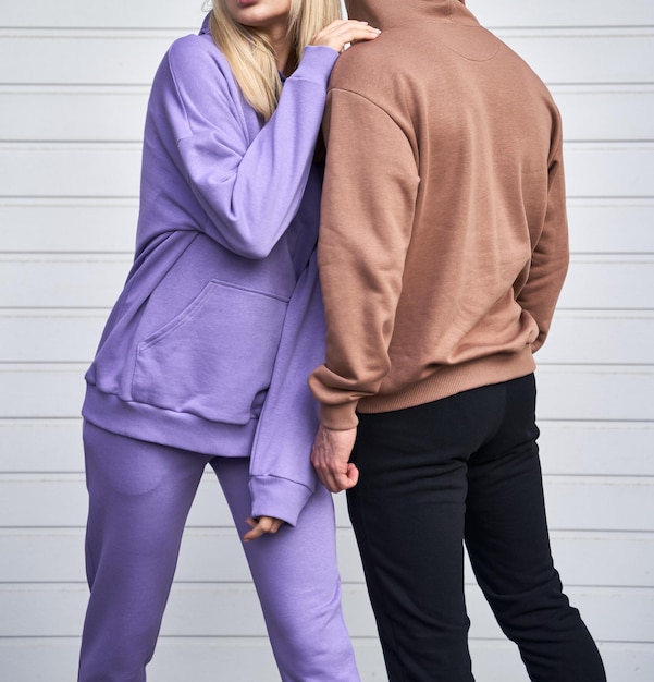 Il giovane uomo barbuto e la ragazza bionda sono in piedi in una felpa con cappuccio semplice per la stampa del logo Mockup di abbigliamento per felpa con cappuccio Autunno giovani streetwear