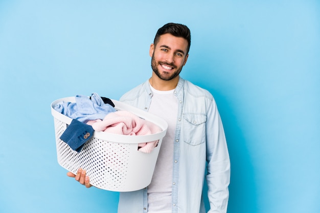 Il giovane uomo bello che fa la lavanderia ha isolato felice, sorridente e allegro