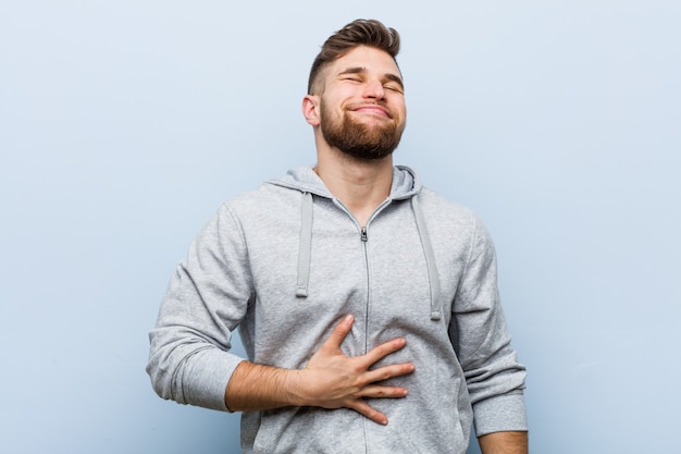 Il giovane uomo bello di forma fisica tocca la pancia, sorride delicatamente, mangia e la soddisfazione.