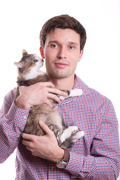 Il giovane uomo bianco carino tiene teneramente un gatto nelle sue mani su uno sfondo bianco