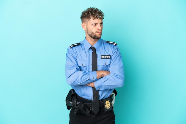 Il giovane uomo biondo della polizia ha isolato il bianco su sfondo blu facendo gesti di dubbi mentre solleva le spalle