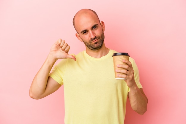 Il giovane uomo calvo caucasico che tiene un caffè da asporto isolato su sfondo rosa si sente orgoglioso e sicuro di sé, esempio da seguire.