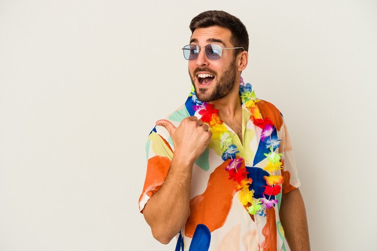 Foto il giovane uomo caucasico che balla su una festa hawaiana isolata su sfondo bianco punta con il pollice lontano, ridendo e spensierato.