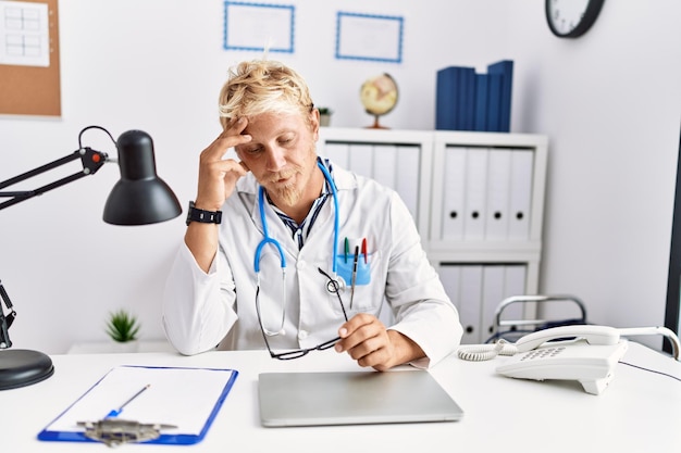 Il giovane uomo caucasico che indossa l'uniforme del medico ha sottolineato il lavoro in clinica