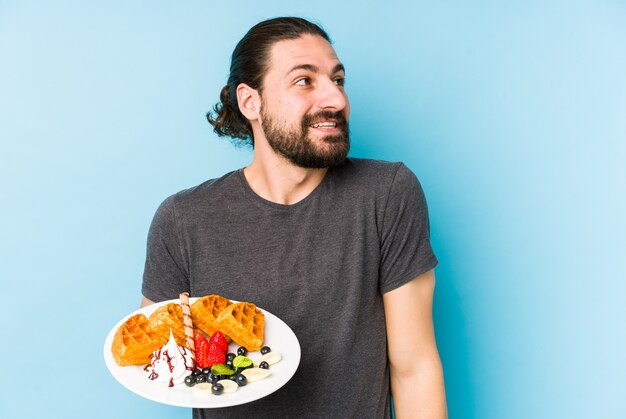 Il giovane uomo caucasico che mangia un dessert della cialda ha isolato il sogno di raggiungere obiettivi e scopi