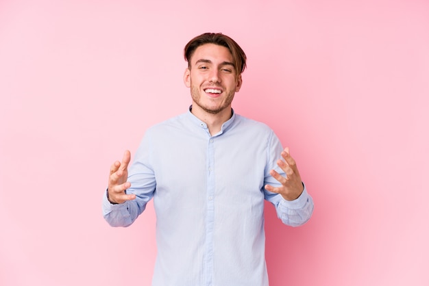 Il giovane uomo caucasico che posa in una parete rosa ha isolato la risata allegra molto. Concetto di felicità.