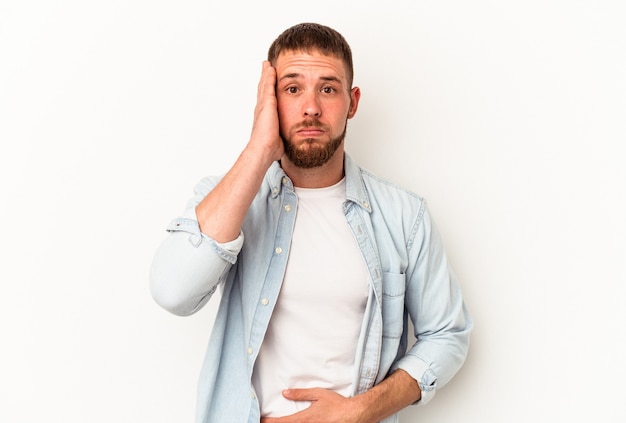 Il giovane uomo caucasico con diastema isolato su sfondo bianco soffia sulle guance, ha un'espressione stanca. Concetto di espressione facciale.