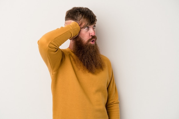 Il giovane uomo caucasico dello zenzero con la barba lunga isolato su sfondo bianco è scioccato, ha ricordato un incontro importante.