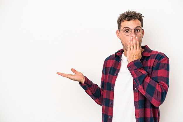 Il giovane uomo caucasico isolato su fondo bianco ha impressionato lo spazio della copia della tenuta sul palmo.