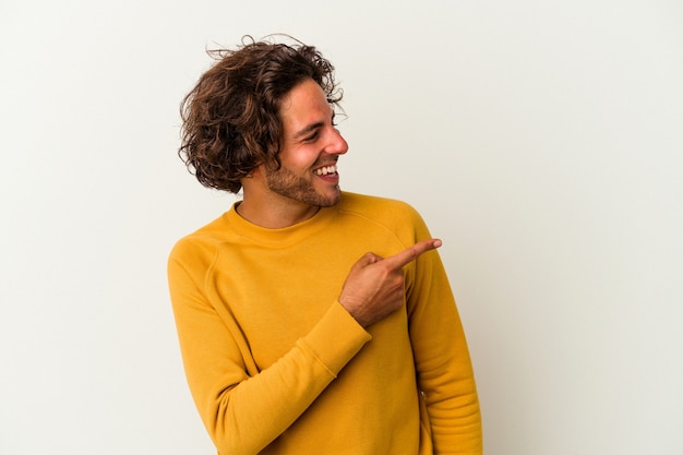 Il giovane uomo caucasico isolato su sfondo bianco guarda da parte sorridente, allegro e piacevole.