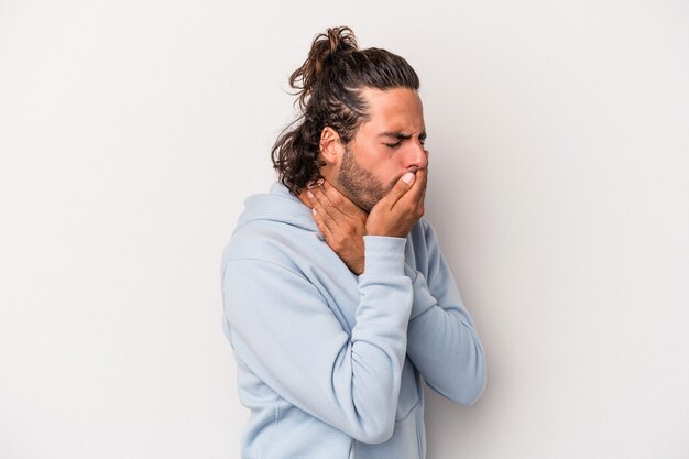 Il giovane uomo caucasico isolato su sfondo grigio soffre di dolore alla gola a causa di un virus o di un'infezione.