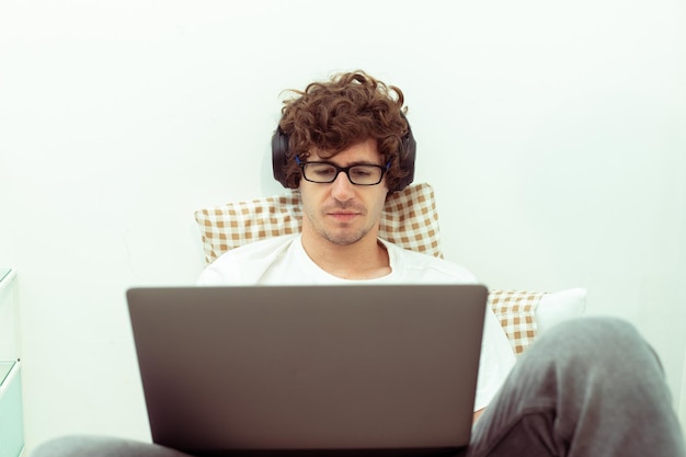 Il giovane uomo caucasico lavora da casa sul laptop e si connette online all'ufficio al chiuso per il posto di lavoro Internet remoto