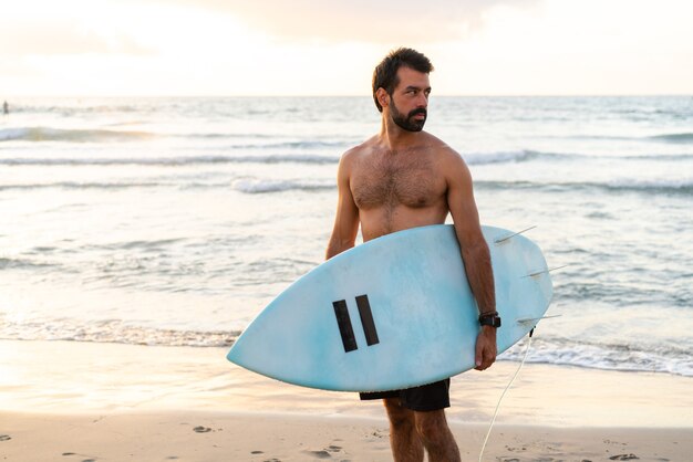 Il giovane uomo caucasico si alza presto per fare surf all'alba