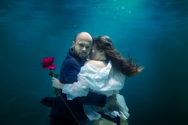 Il giovane uomo d'affari abbraccia la sua donna, dà la rosa, bacia l'amato, sott'acqua. Coppia felice emotiva in stagno. Concetto appuntamento romantico, sorpresa e impegno per lo sviluppo delle relazioni. Copia spazio