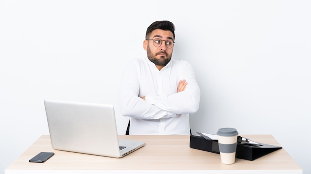 Il giovane uomo d'affari in un posto di lavoro che fa i dubbi gesture mentre solleva le spalle