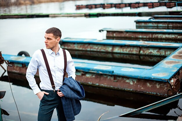 Il giovane uomo d'affari maschio bello sta sul bacino alla stazione della barca